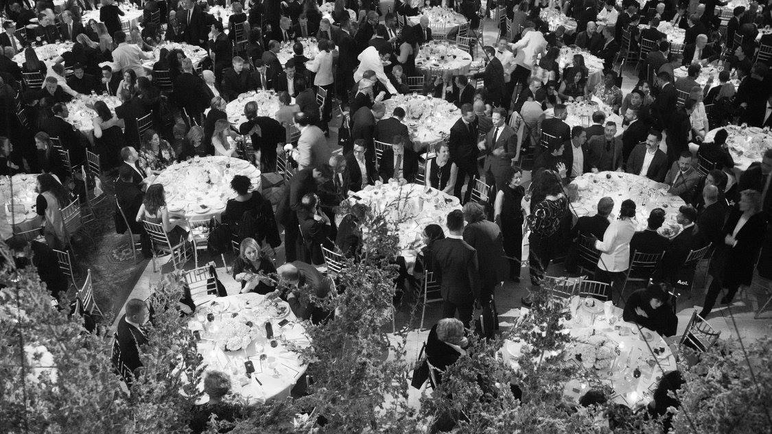 Overhead view of a black-tie gala dinner in New York City produced by Golden Circle's principal, with round banquet tables, candlelight, and tall greenery centerpieces