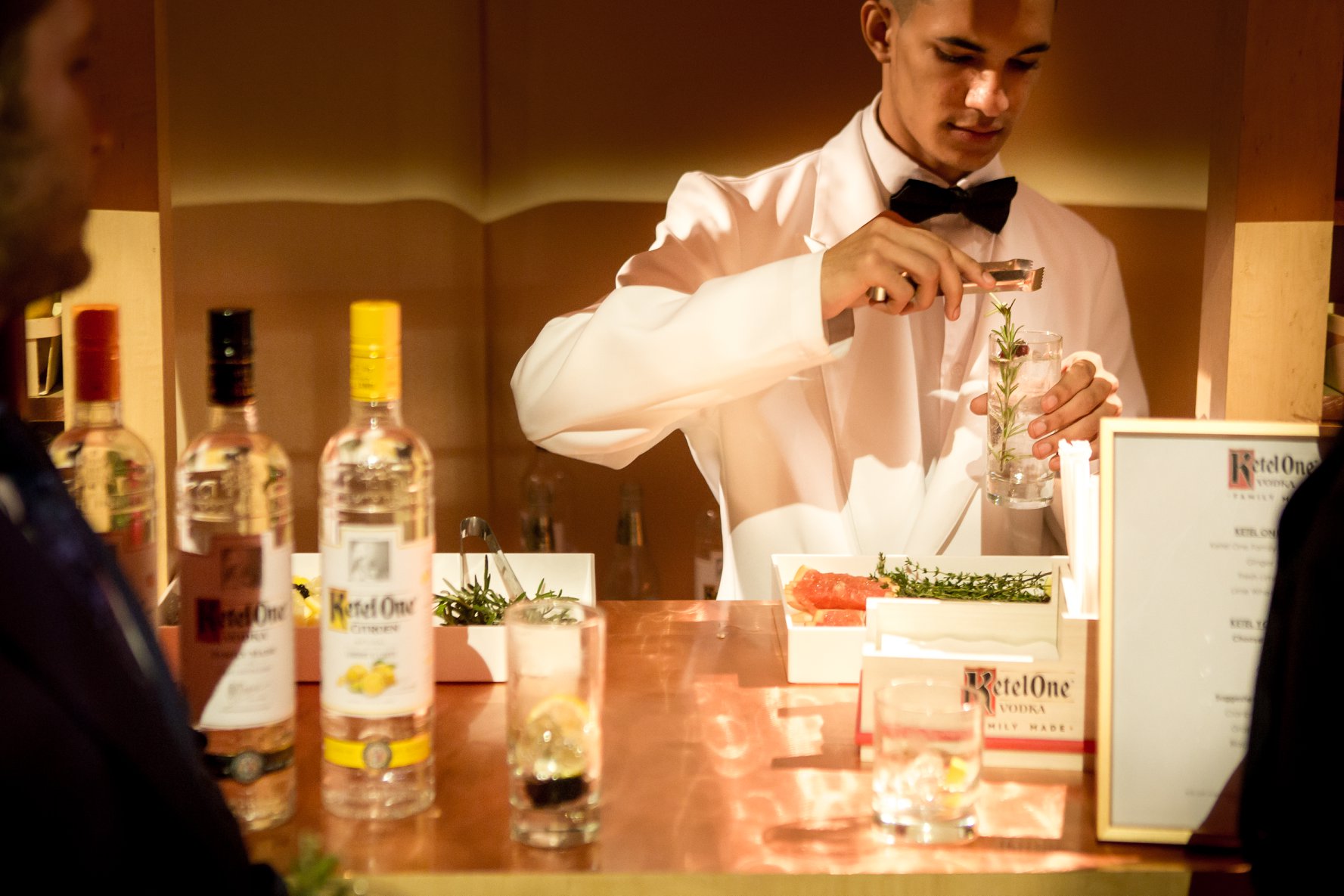 A bartender in a white dinner jacket garnishing a cocktail at a New York City gala produced by Golden Circle's principal